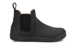A black slip-on Chelsea Boot by Xero Shoes featuring elastic side panels, a pull tab at the back, rounded toe, and textured rubber sole. This simple design showcases visible stitching and a low heel—ideal for everyday styles.