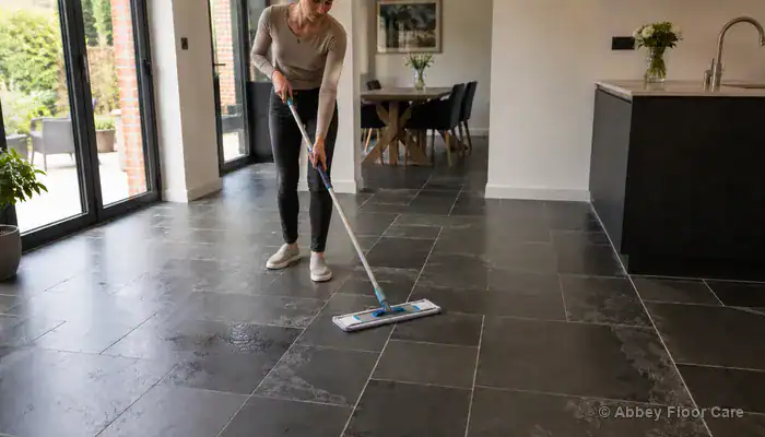 Mopping textured slate tiles using a damp microfiber mop and pH-neutral stone cleaner